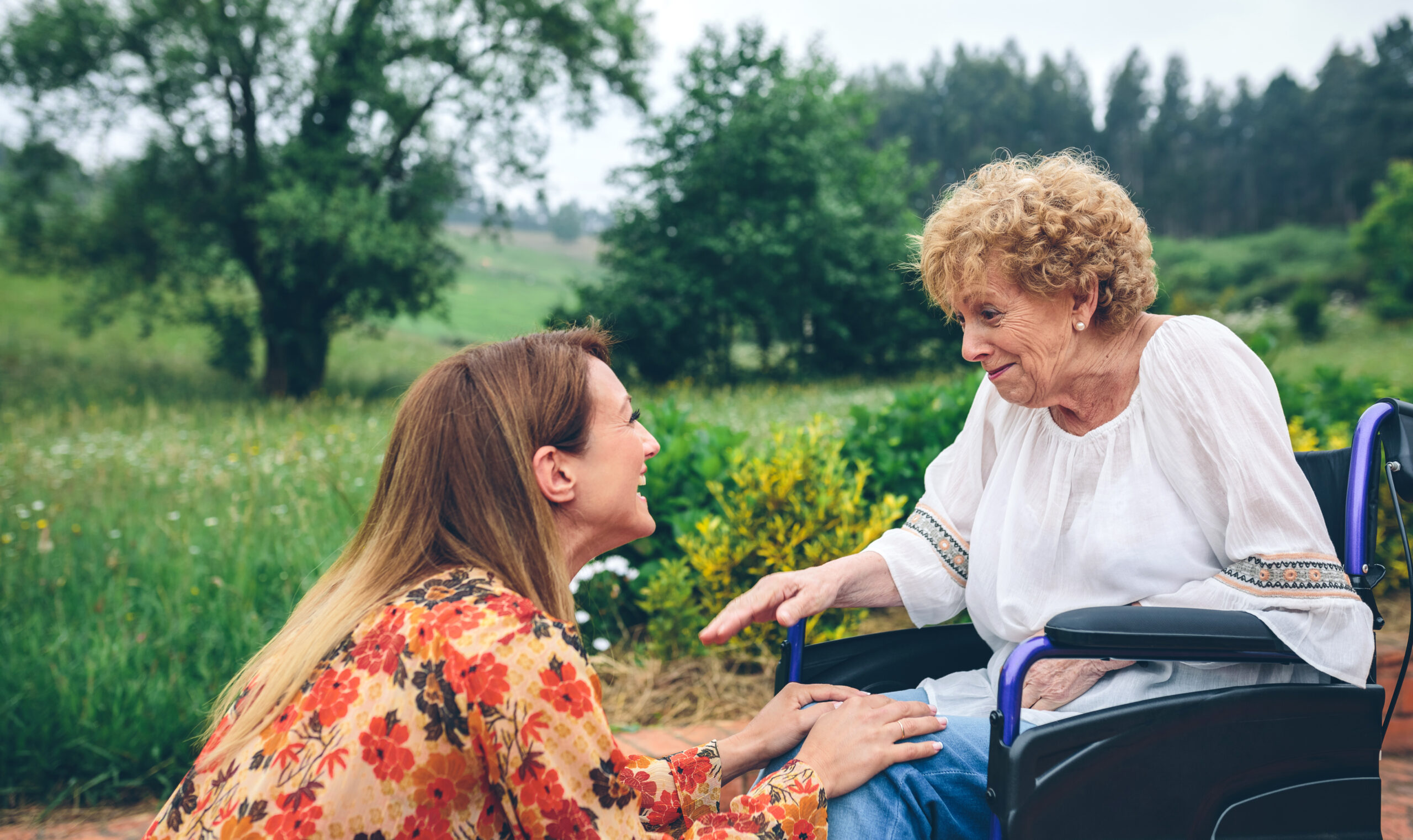 Young woman talking to elderly woman in a wheelchair Memory Care Photo