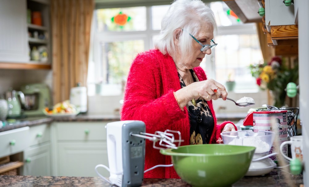 woman in kitchen older woman in read sweater working in kitchen