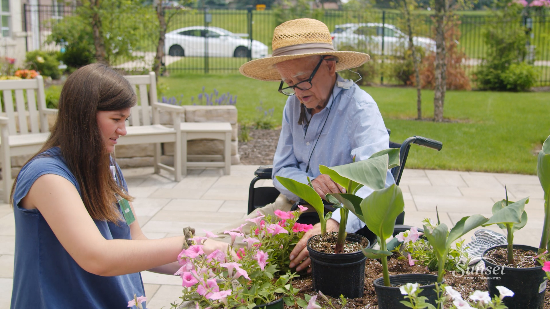Gardening Memory Care Sunset staff member helps a memory care resident plant flowers in a big planter