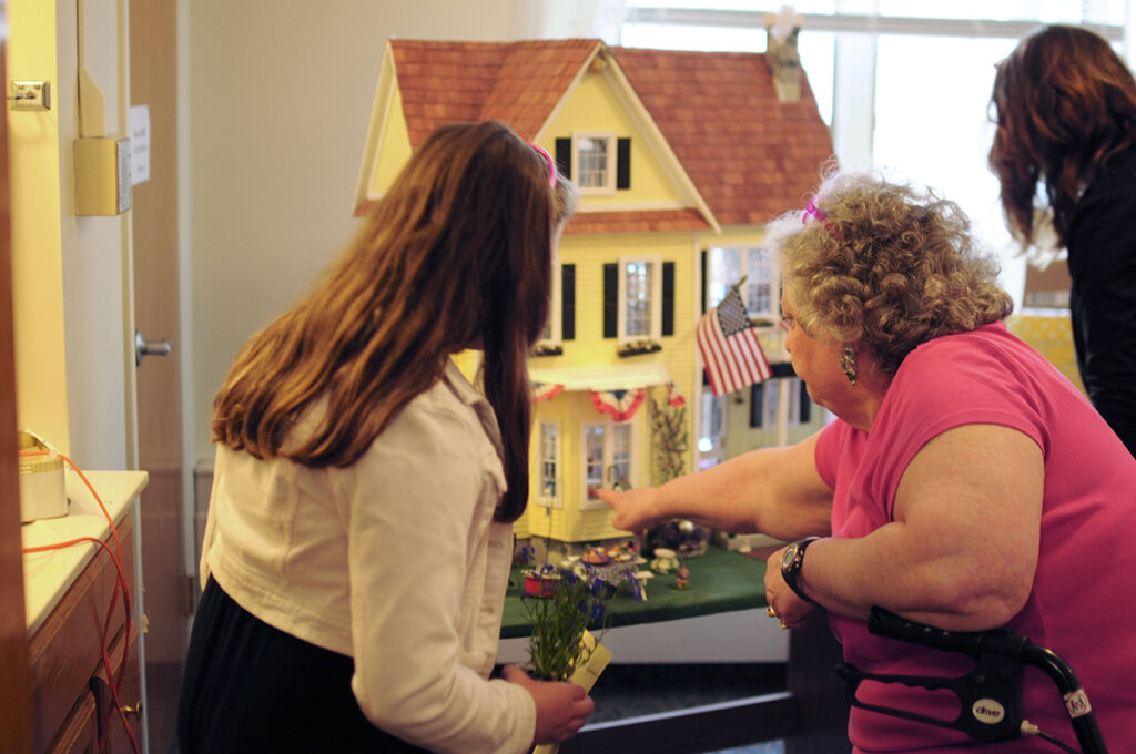 Christian-Haven-Generation Generations interacting with a dollhouse.