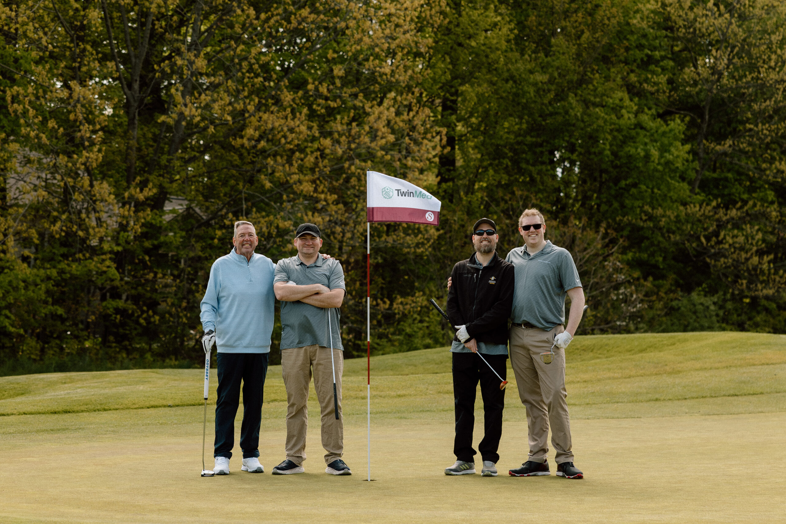 Sunset Golf Outing Men golfing and standing on putting green with branded golf flag.
